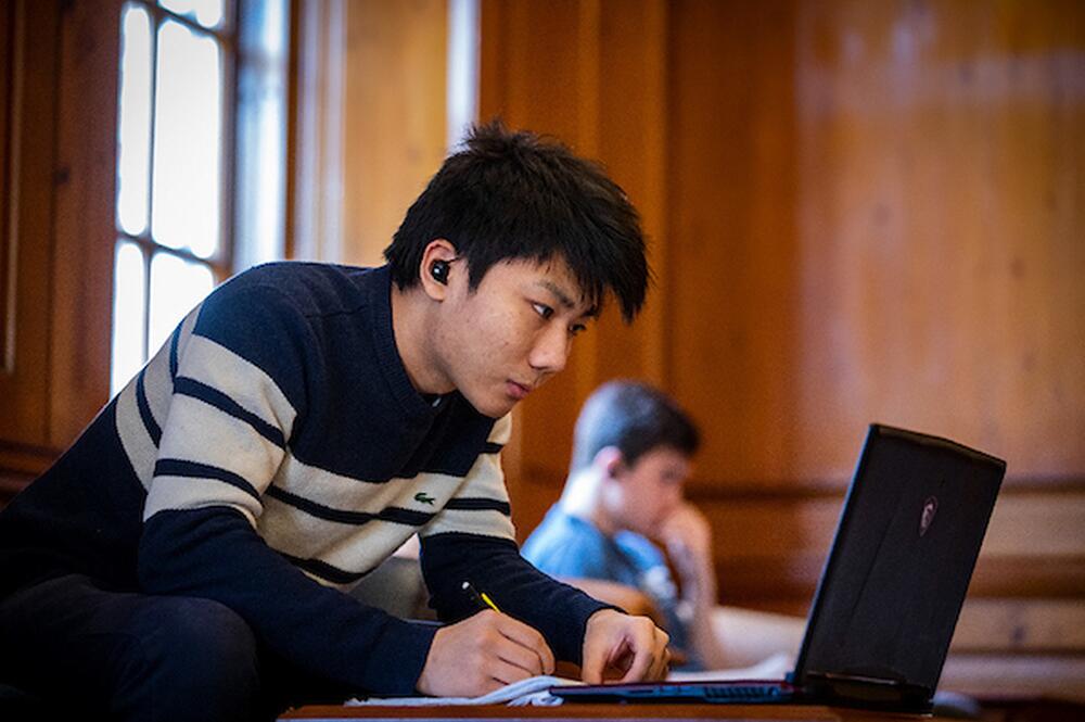 A student in a striped sweater uses a laptop.